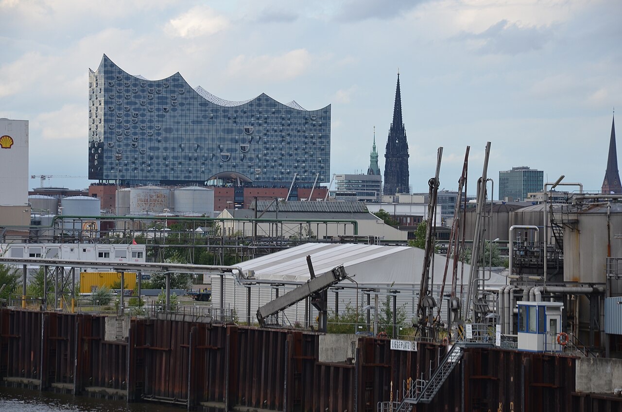 Die Elbphilharmonie in Hamburg mit ihrer wellenförmigen Glasfassade auf dem historischen Backsteinsockel, im Vordergrund die Elbe